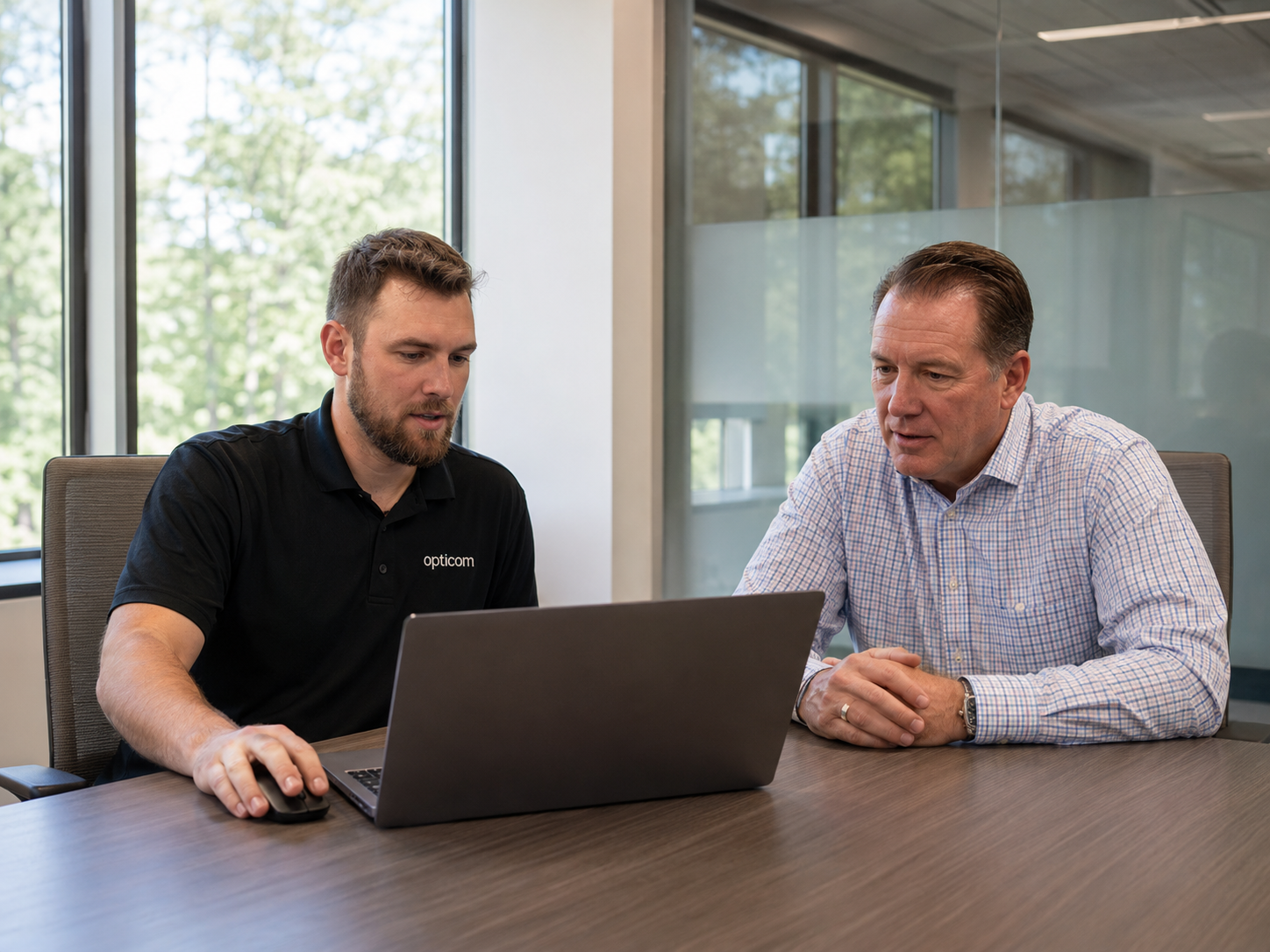 Foto: IT-Techniker und Kundenvertreter besprechen Projektabschluss am Besprechungstisch mit Notebook