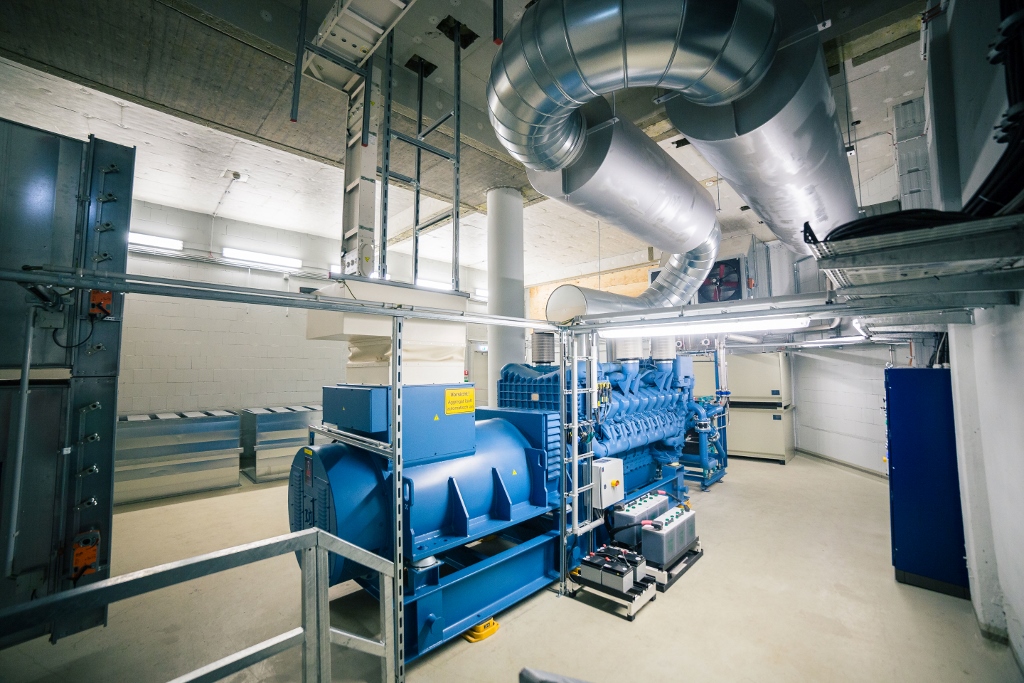 Industrielle Maschinenraum mit großem blauem Dieselgenerator, Rohrleitungssystem und Steuerungsanlage